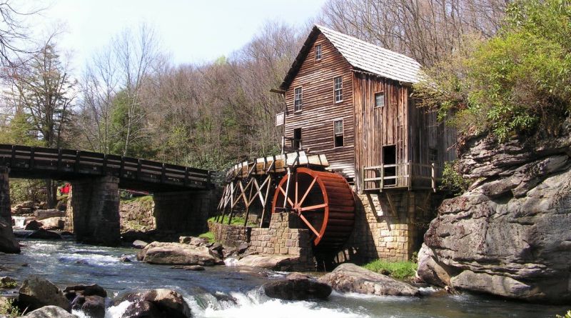 A creekside gristmill with a red water wheel